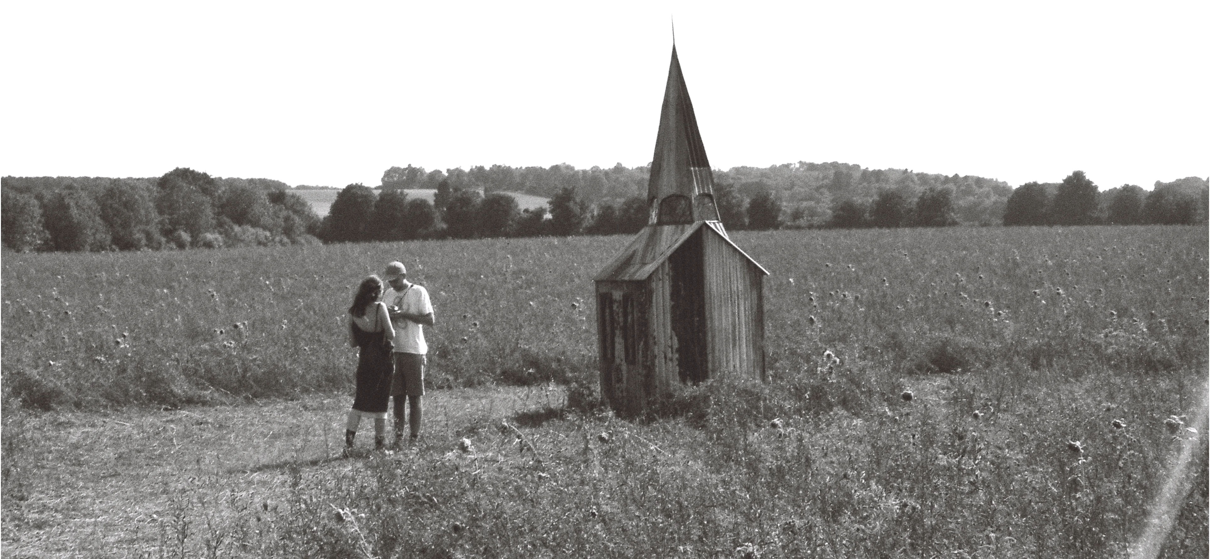 Eve and Tom in a field near a chapel